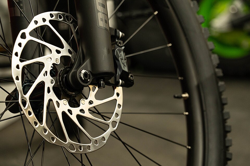 A bike disc brake: the silver rotor and the brake caliper mounted on the fork