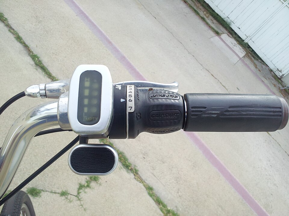 A thumb throttle paddle under the grip of an e-bike, next to a battery level indicator