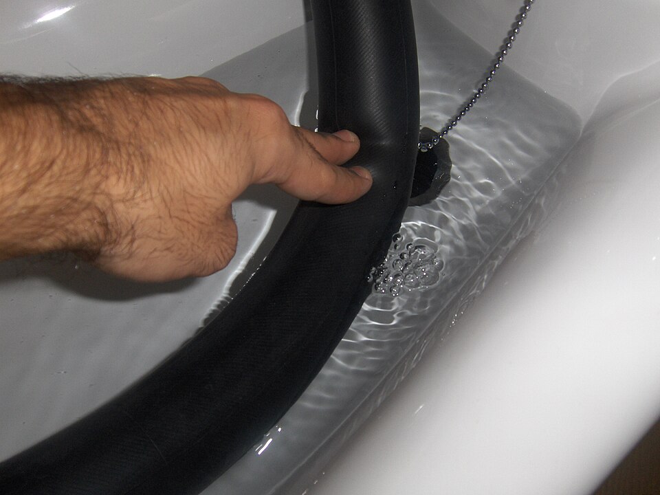 An inner tube held underwater, with air bubbles showing where the puncture is