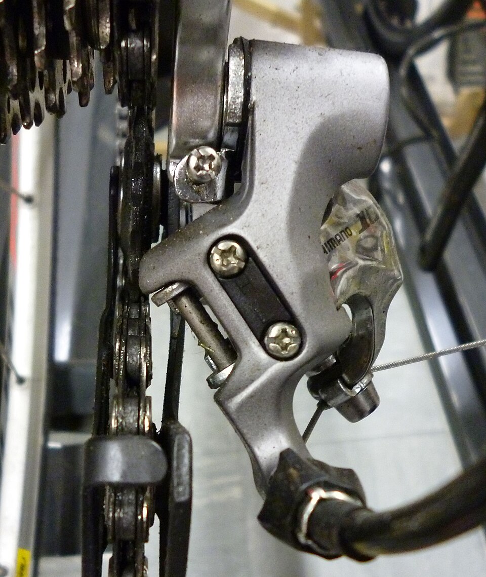 Close-up of a rear derailleur showing its cable clamp and small adjustment screws